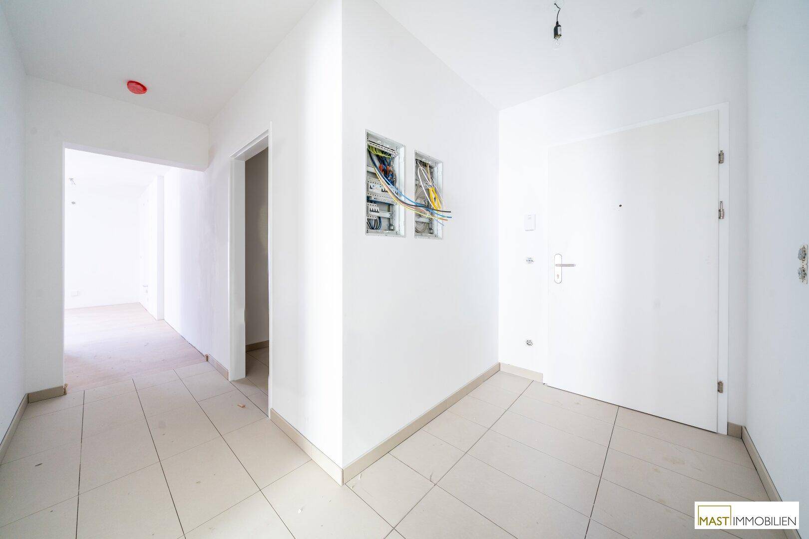 Heller Flur mit Fliesenboden und sichtbarem Sicherungskasten, der den Eingangsbereich der Wohnung zeigt.