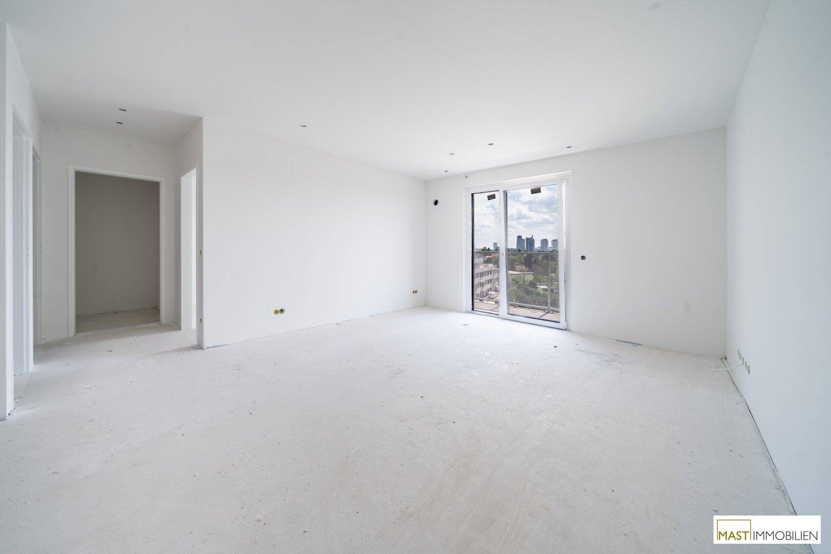 Heller, unmöblierter Raum im Rohbauzustand mit Zugang zu einem Balkon und Stadtblick.