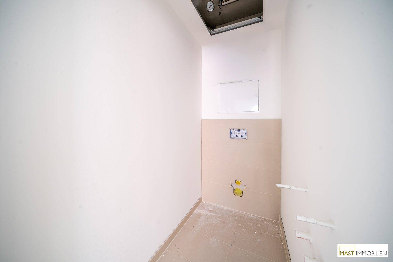 Separates WC mit moderner Vorinstallation für Toilette und hellen Fliesen.