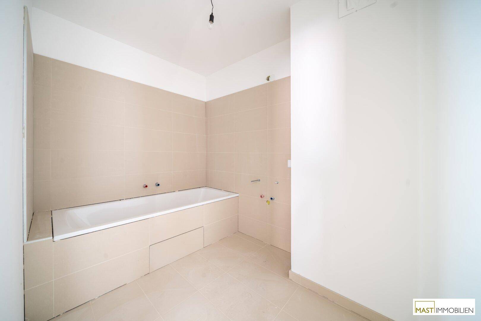 Modernes Badezimmer mit eingebauter Badewanne und beigefarbenen Wand- und Bodenfliesen.