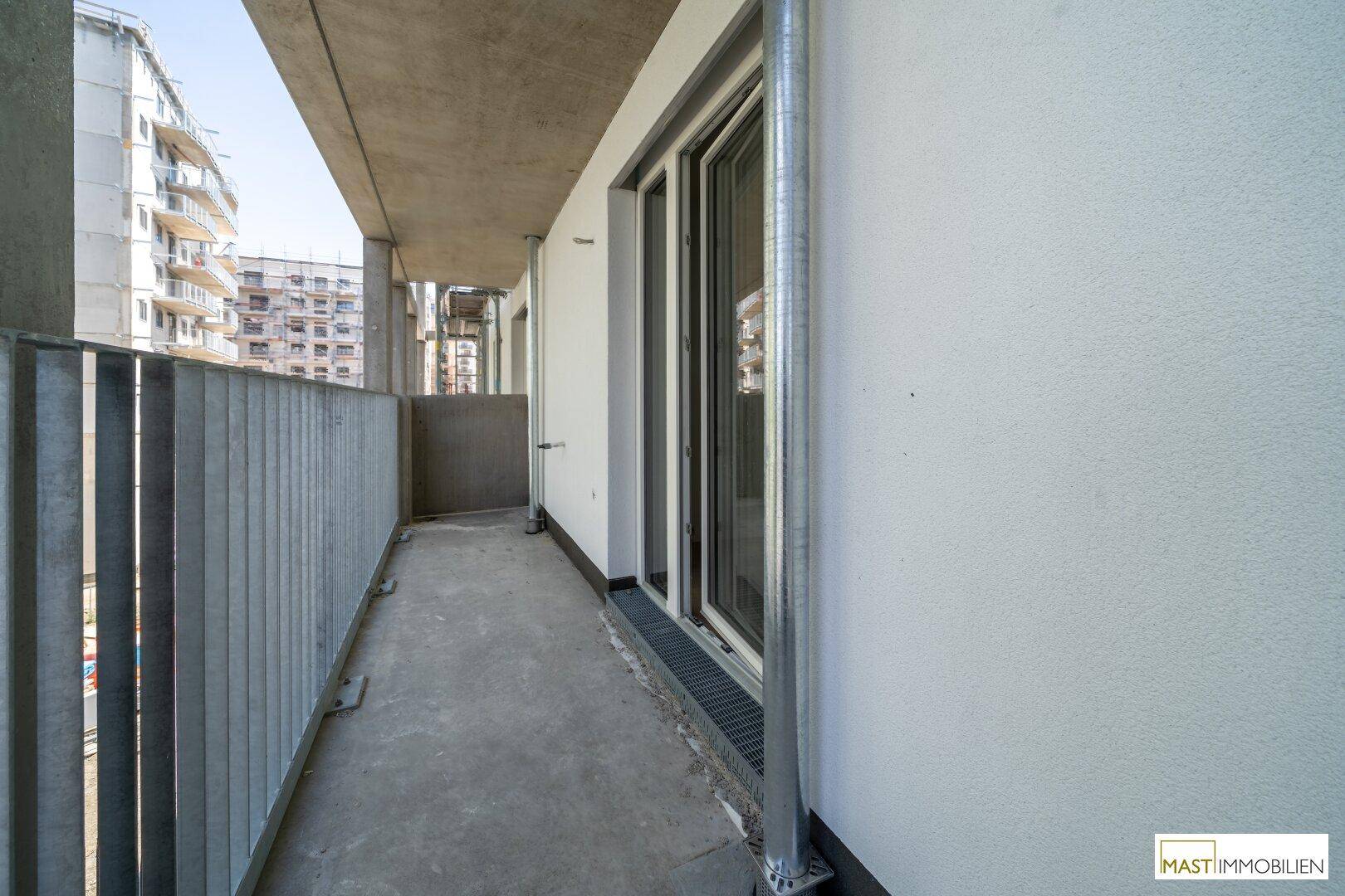 Balkon mit Schiebetür und Metallgeländer, der einen Zugang zum Außenbereich bietet.