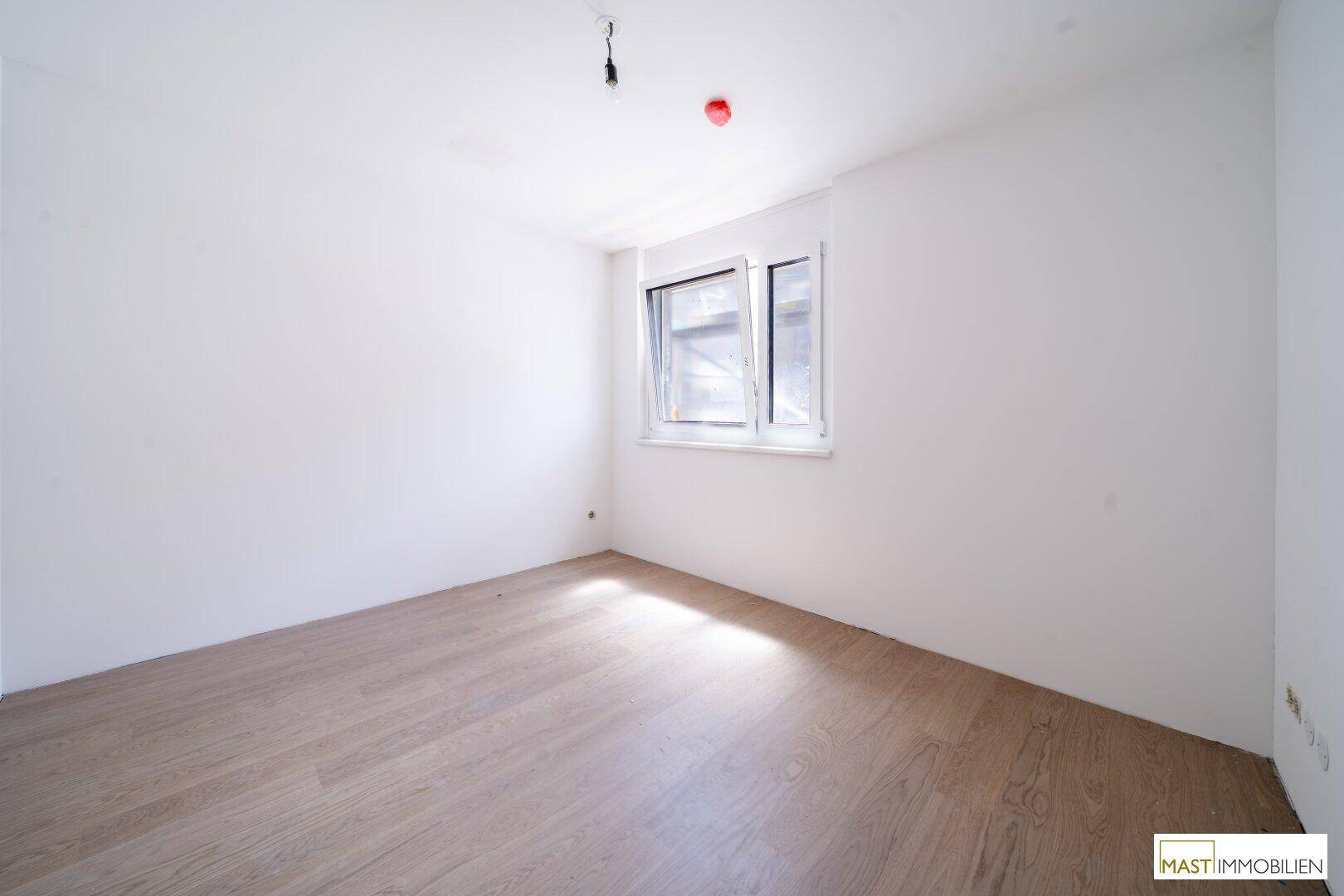Helles, unmöbliertes Schlafzimmer mit Parkettboden und einem Fenster, bereit zum Einzug.