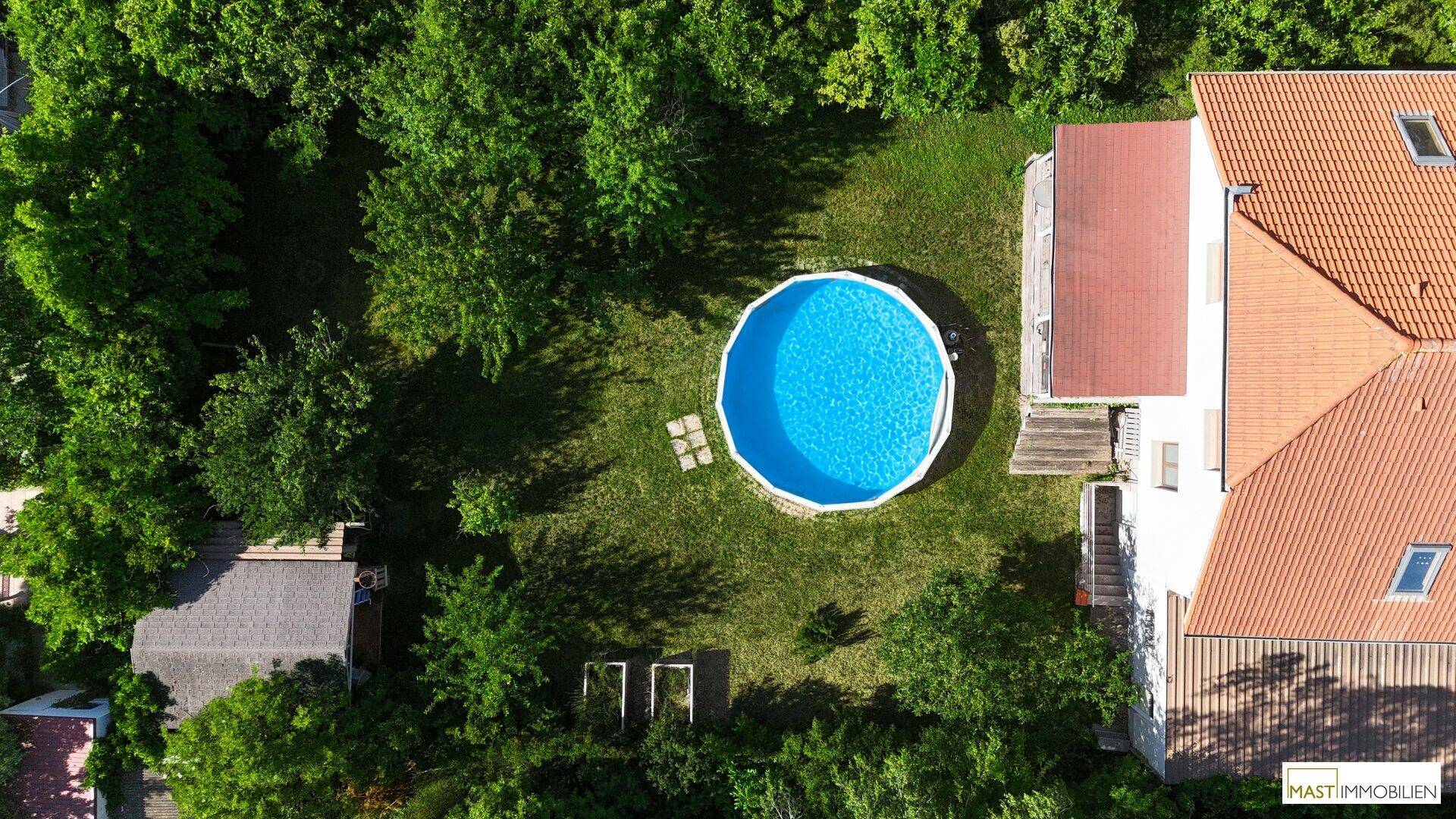 Draufsicht auf das Grundstück mit Haus, großem Garten und rundem oberirdischem Pool.