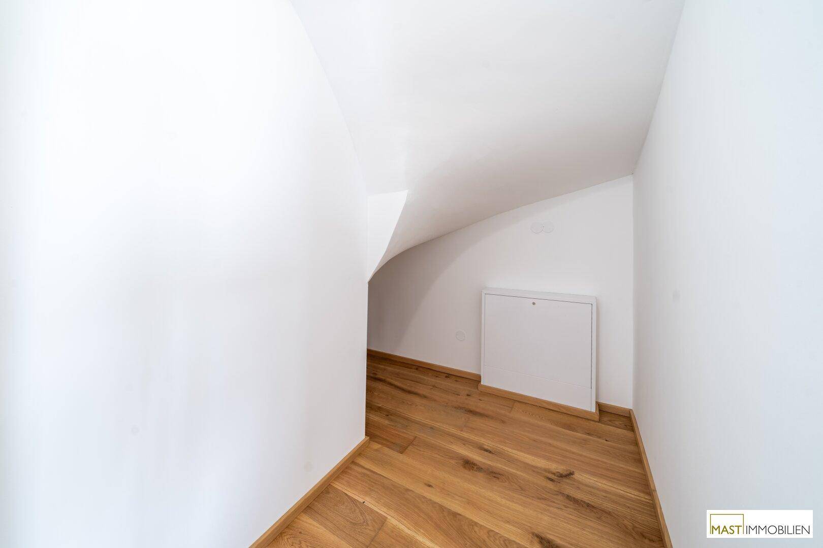 Praktischer Abstellraum unter einer Dachschräge mit Holzboden für zusätzlichen Stauraum.