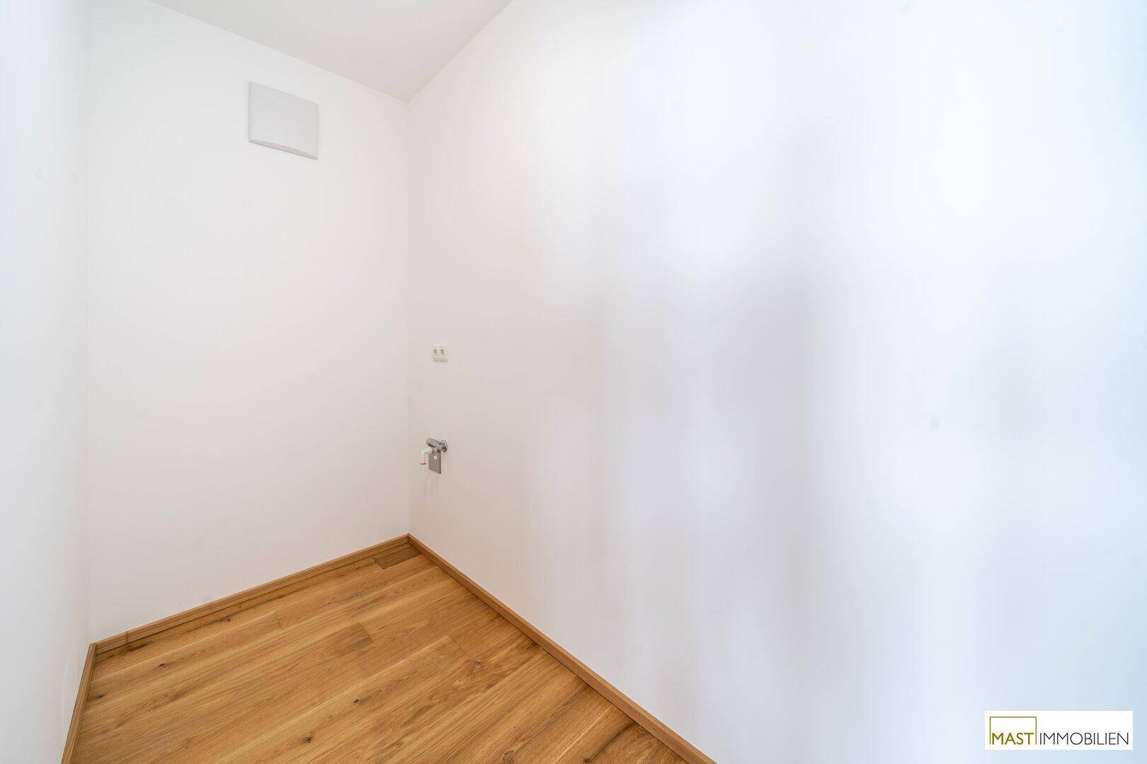 Kleiner Hauswirtschaftsraum mit Anschlüssen für Geräte und Holzboden.