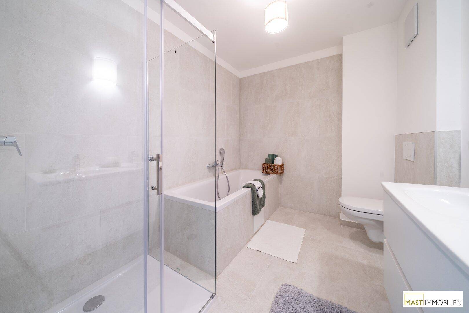Modernes Badezimmer mit Dusche, Badewanne, WC und eleganten grauen Fliesen.