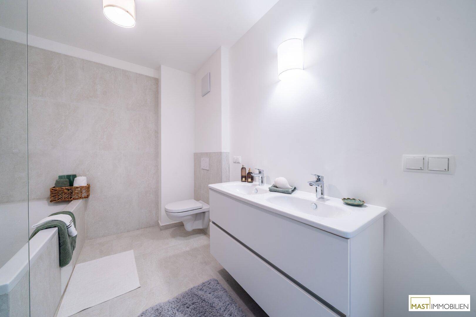 Helles Badezimmer mit Doppelwaschbecken, wandhängendem WC und modernen Armaturen.