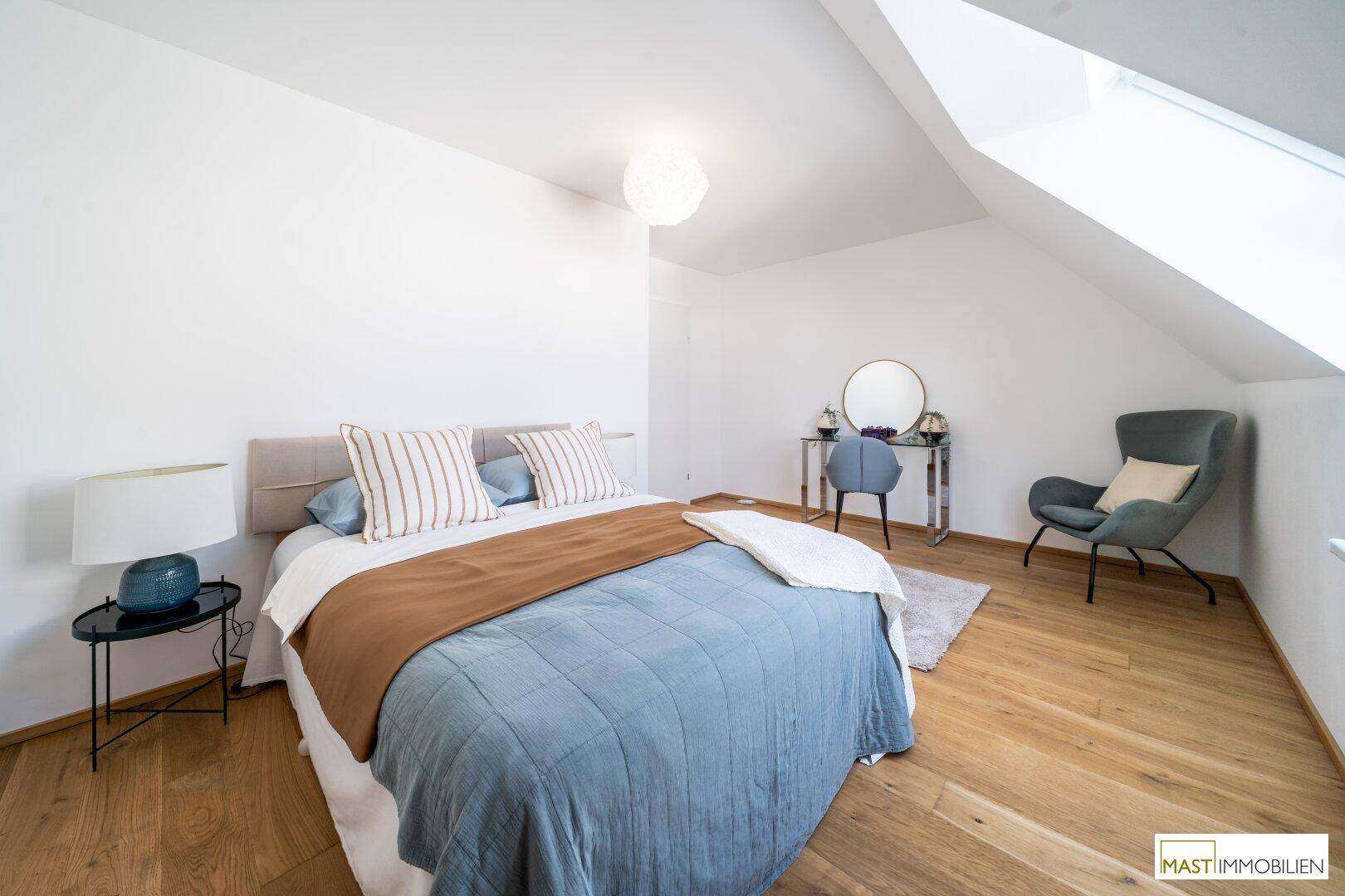 Gemütliches Schlafzimmer mit Doppelbett, Schminktisch und Dachschräge mit Fenster.