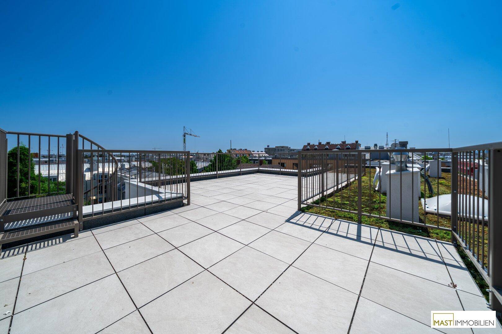 Weitläufige Dachterrasse mit Fliesenboden und weitem Blick über die Umgebung.