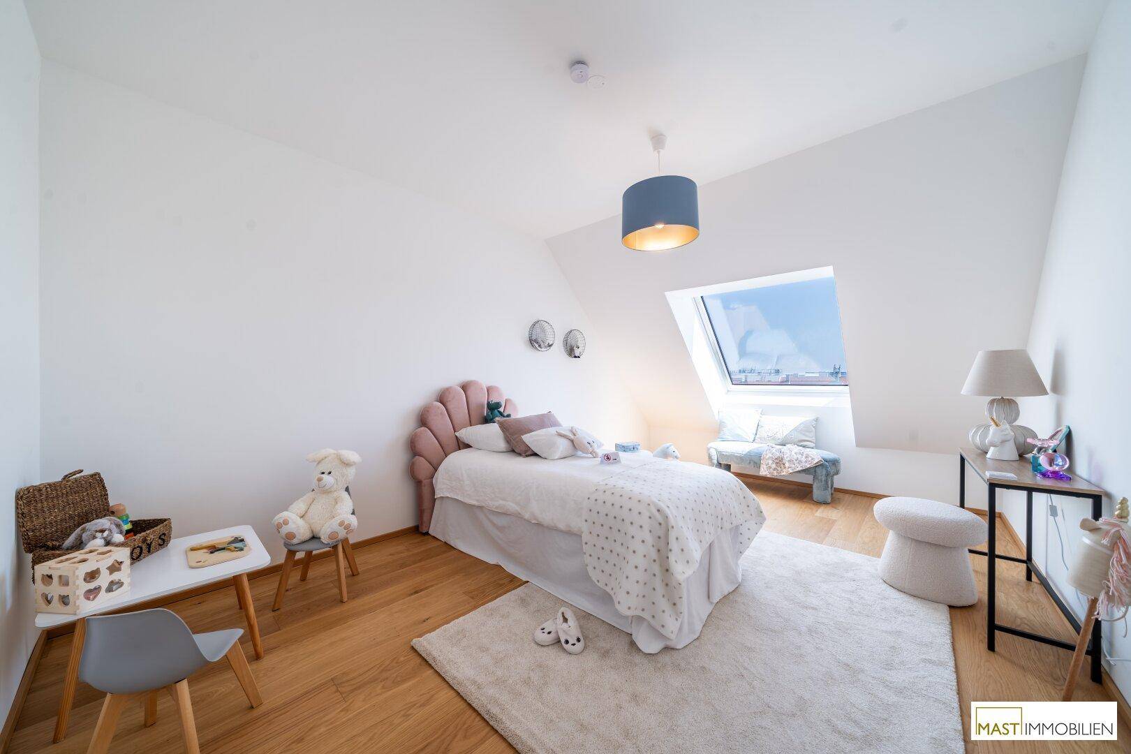 Kinderzimmer mit Dachschräge, Holzboden und einem großen Dachfenster, hell und freundlich.