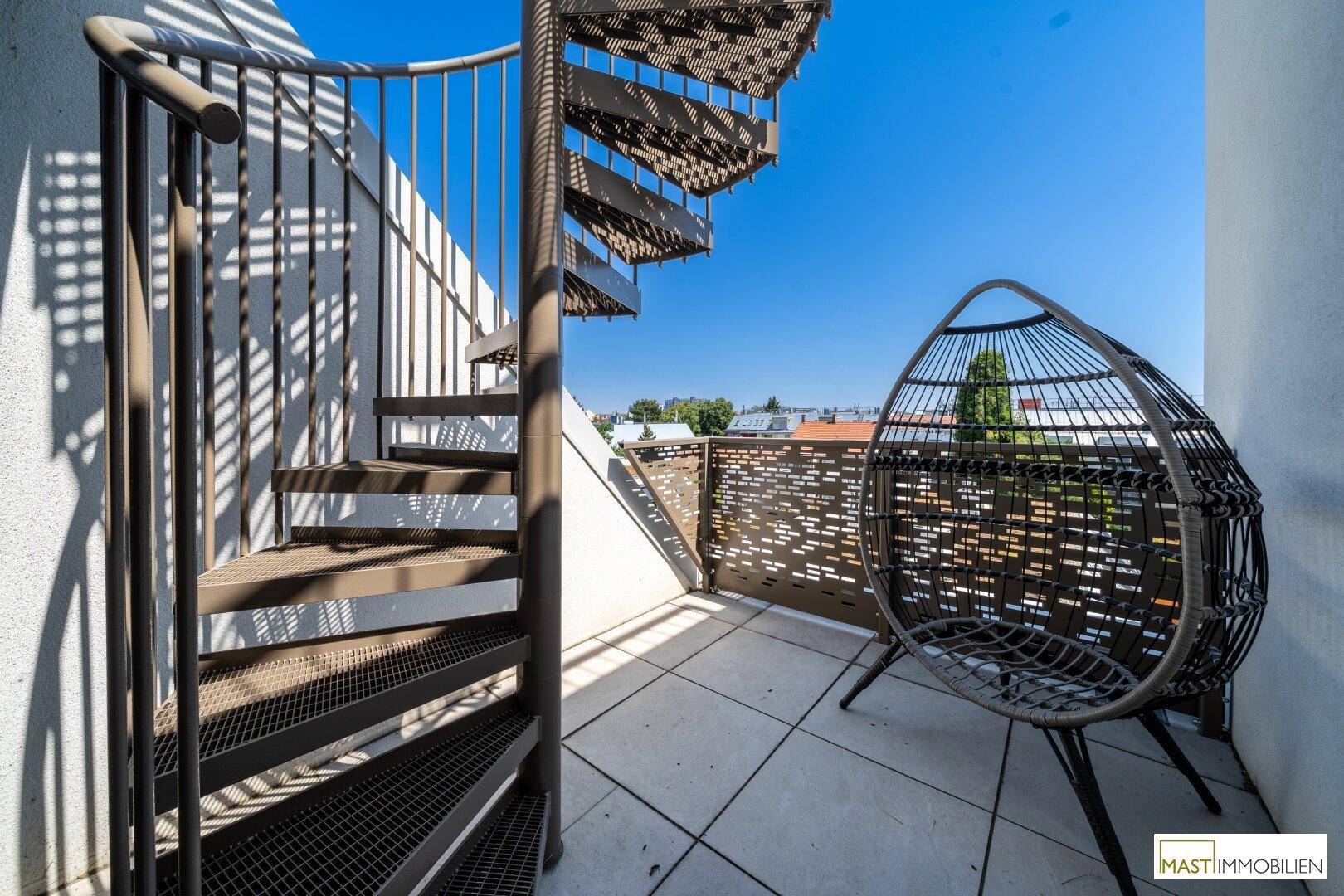 Sonnenterrasse mit Wendeltreppe und Sitzgelegenheit, ideal zum Entspannen im Freien.