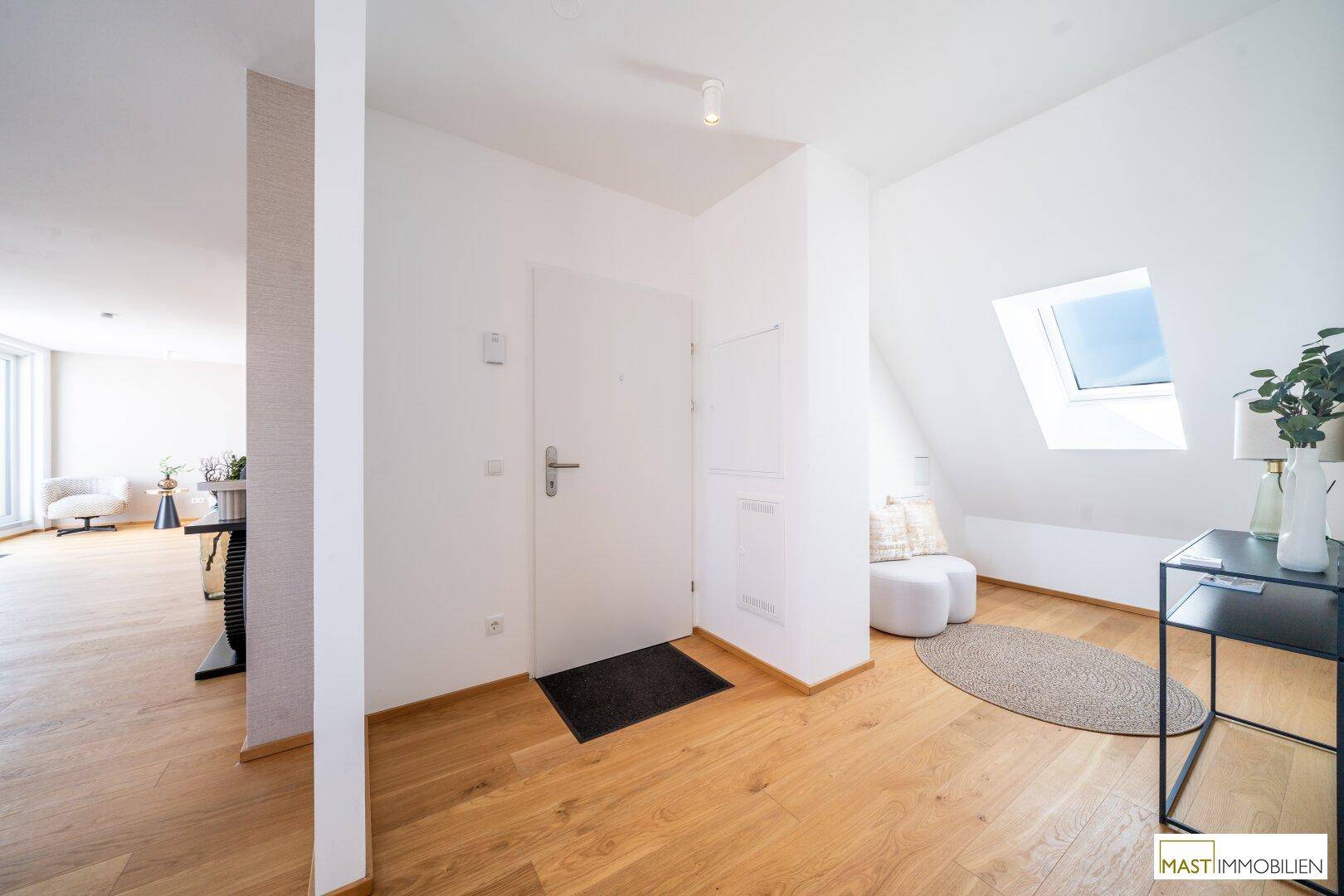 Heller Eingangsbereich mit Holzboden, Dachfenster und Zugang zu weiteren Räumen.