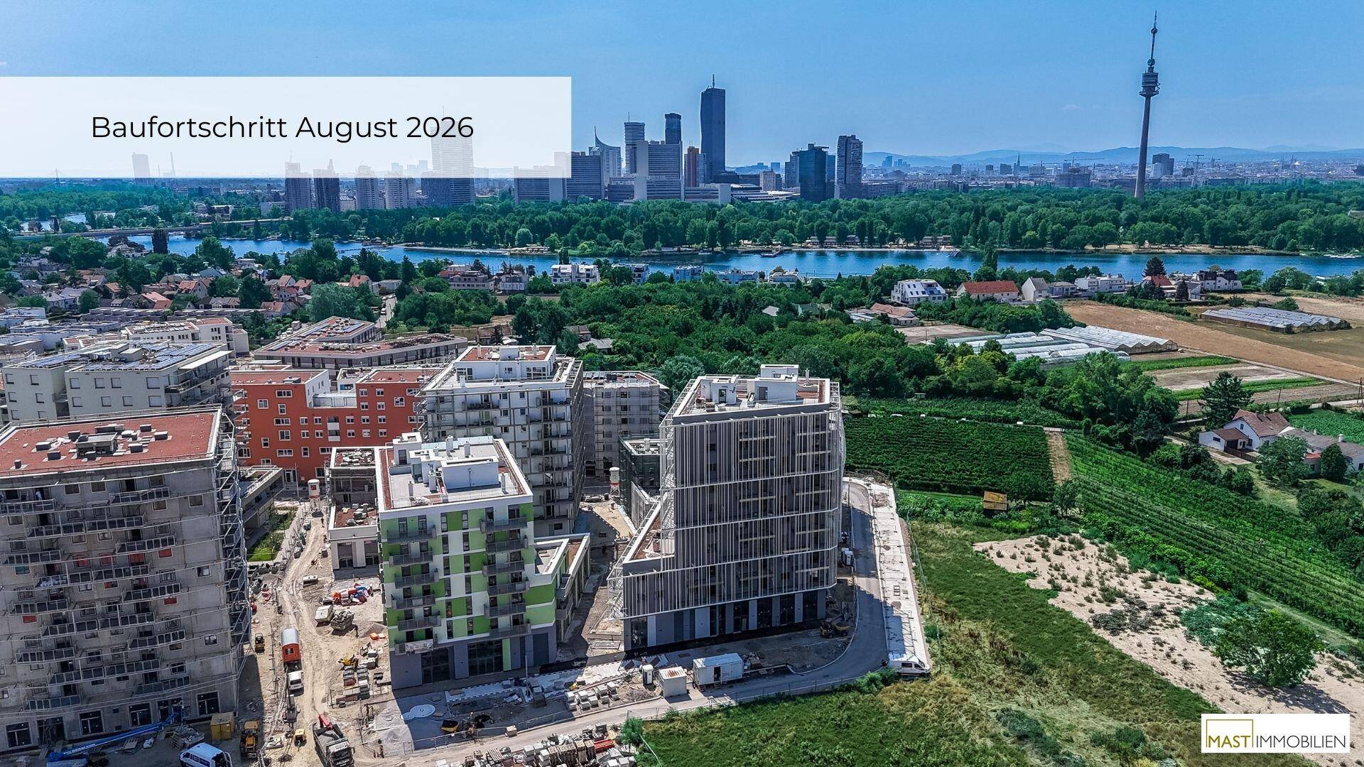 Luftaufnahme des Baufortschritts im August 2026 mit modernen Gebäuden und Blick auf die Stadt und den Fluss.