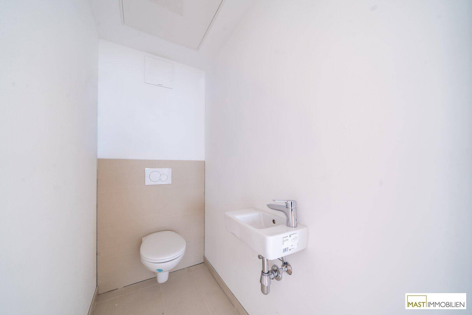 Modernes Gäste-WC mit wandhängender Toilette und kleinem Waschbecken.