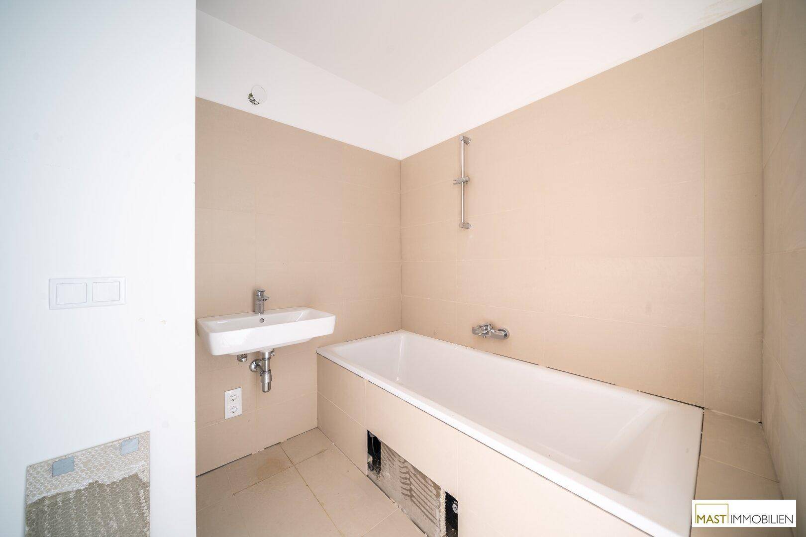 Unfertiges Badezimmer mit Badewanne und Waschbecken, bereit für die Endmontage.