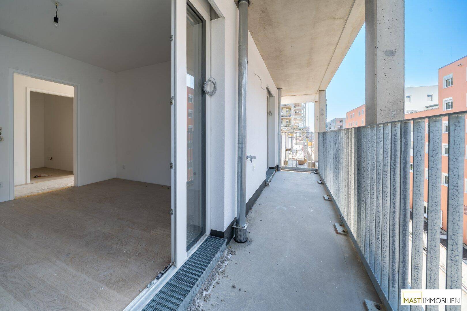 Langer Balkon mit Metallgeländer und Zugang zu einem hellen Innenraum.