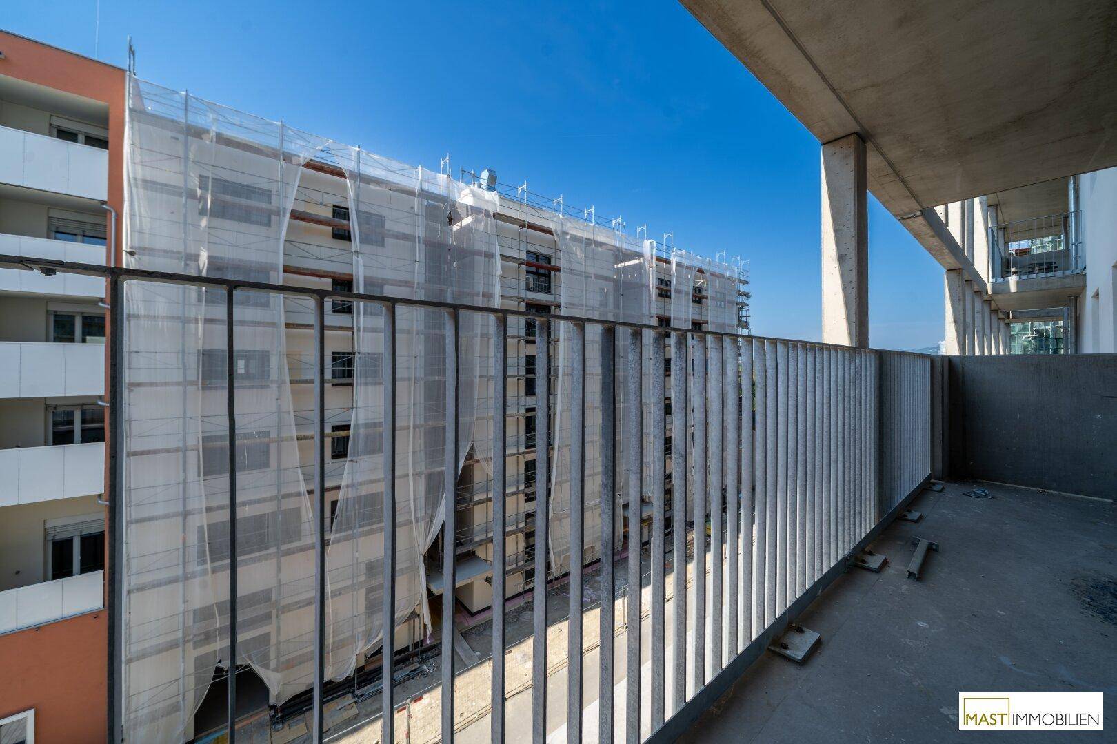 Balkon mit Blick auf eine weitere Baustelle und umliegende Gebäude.