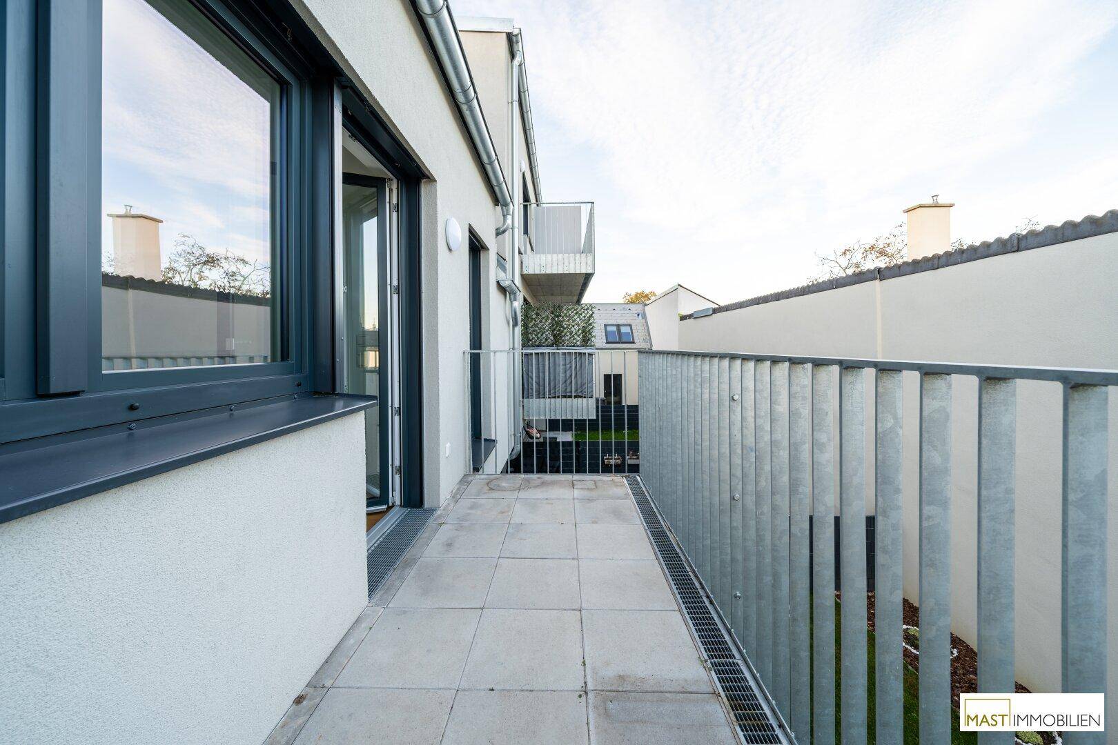 Heller Balkon mit Fliesenboden und modernem Metallgeländer, ideal für entspannte Stunden im Freien.