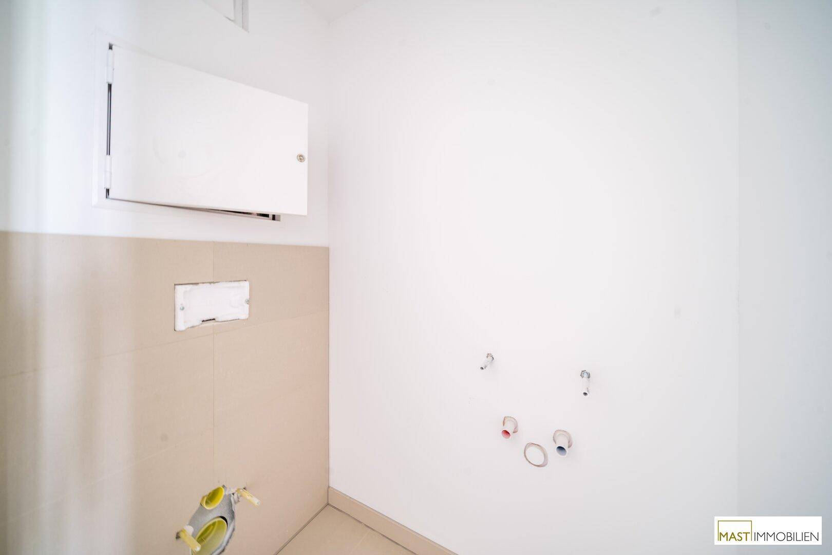Kleiner Raum mit Fliesen an den Wänden und Anschlüssen für ein WC und Waschbecken, ideal als Gästetoilette.