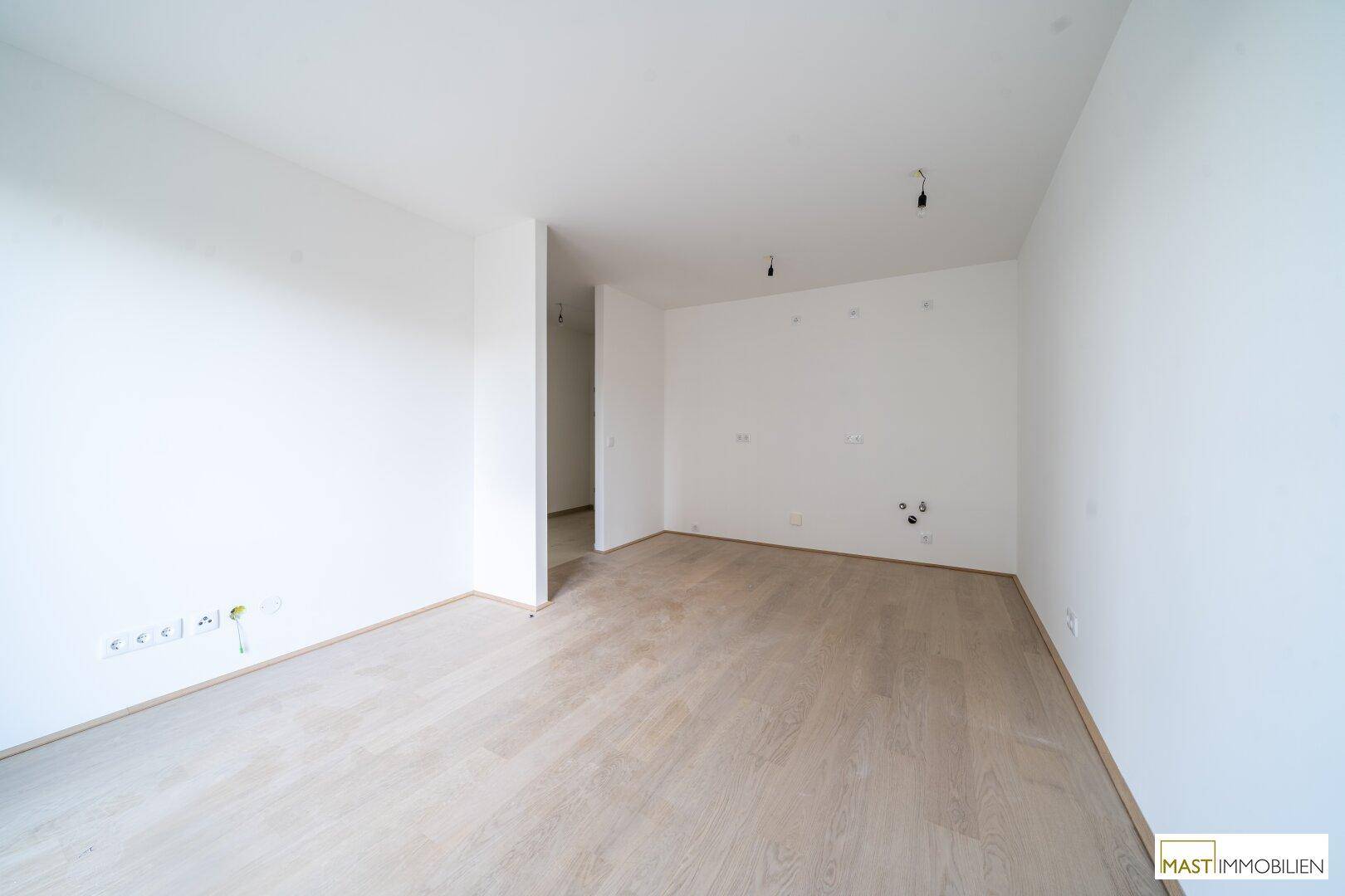 Heller Innenraum mit Parkettboden und einem Durchgang zu einem weiteren Bereich der Wohnung.