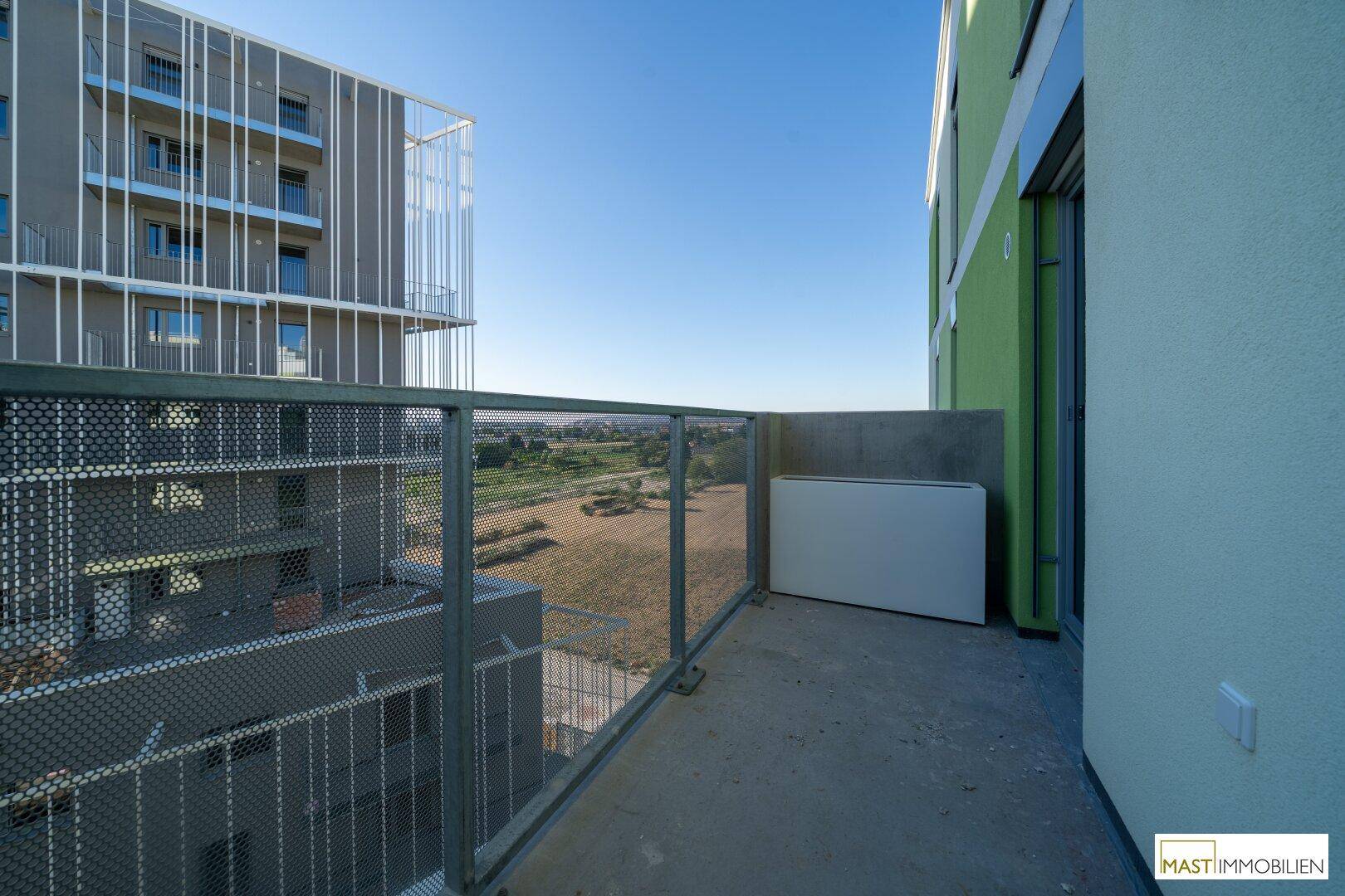Moderner Balkon mit Metallgeländer und weitem Blick über die Umgebung und andere Gebäude.