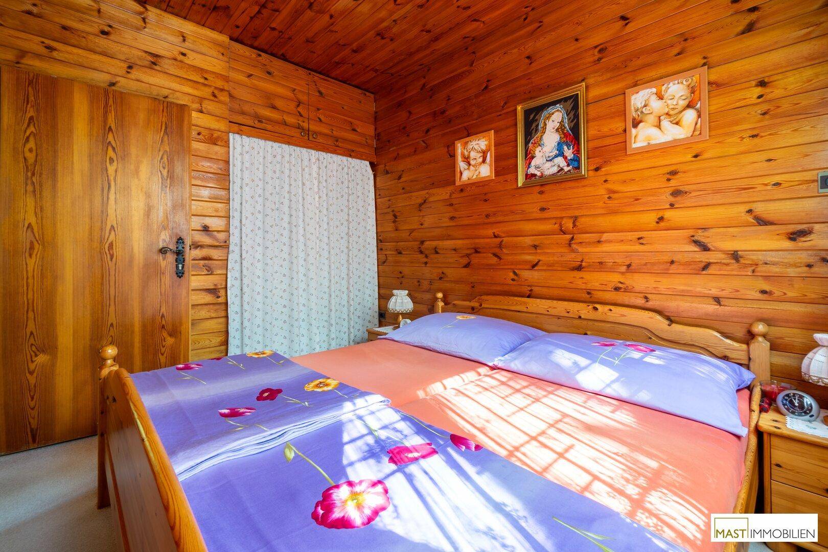 Gemütliches Schlafzimmer mit Holzwänden, Doppelbett und traditioneller Einrichtung.