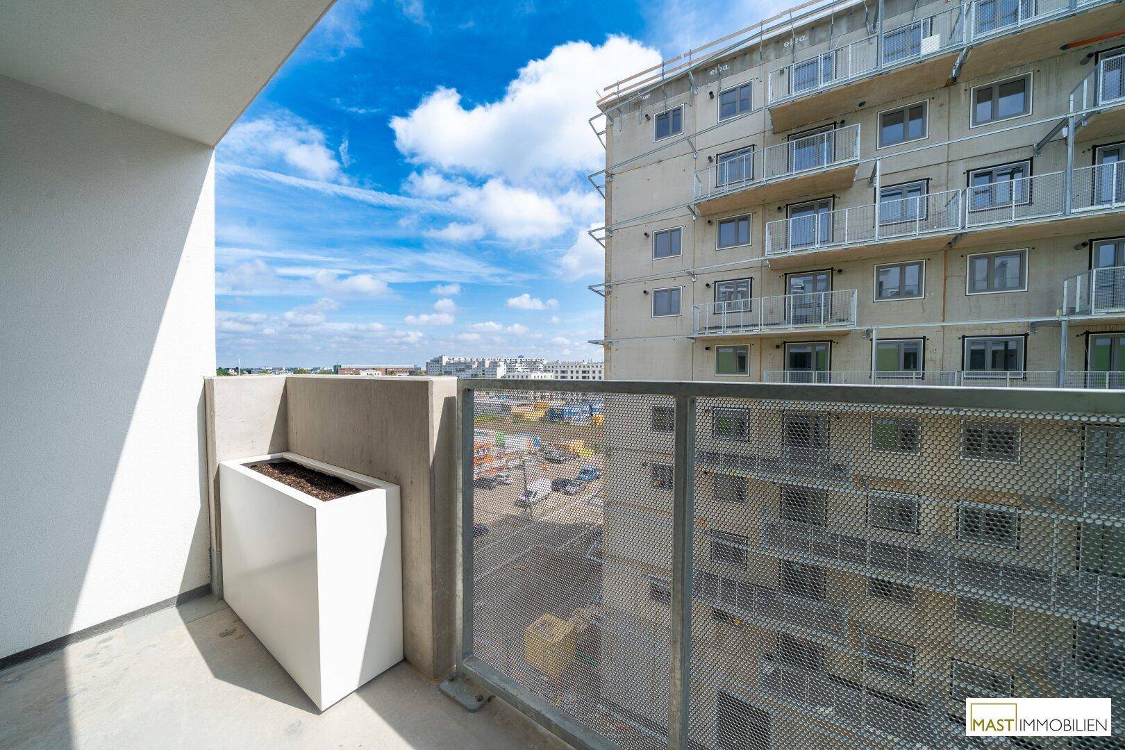 Balkon mit Blick auf ein modernes Wohngebäude und den Himmel.
