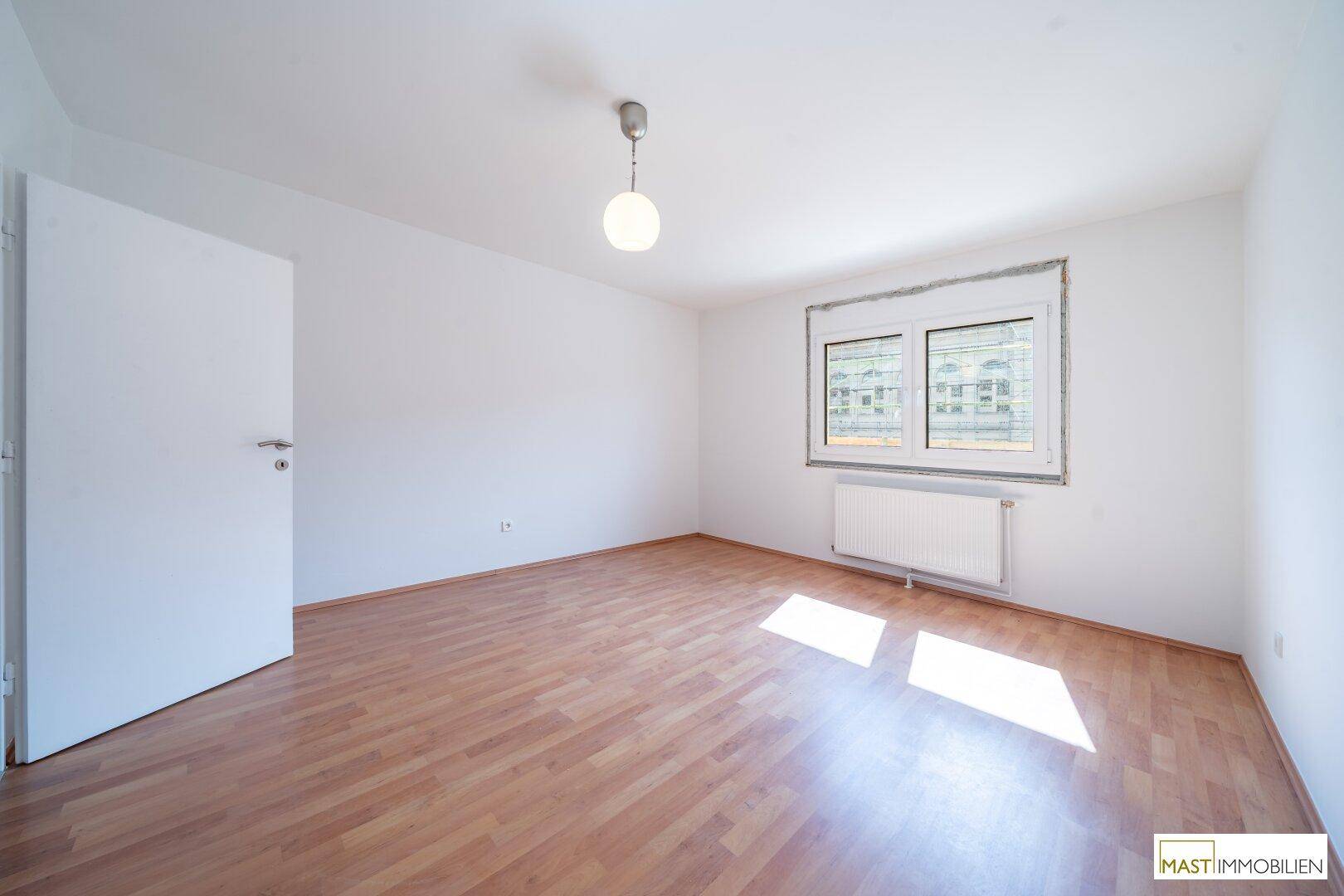 Geräumiges Schlafzimmer mit Laminatboden und viel Tageslicht durch das Fenster.