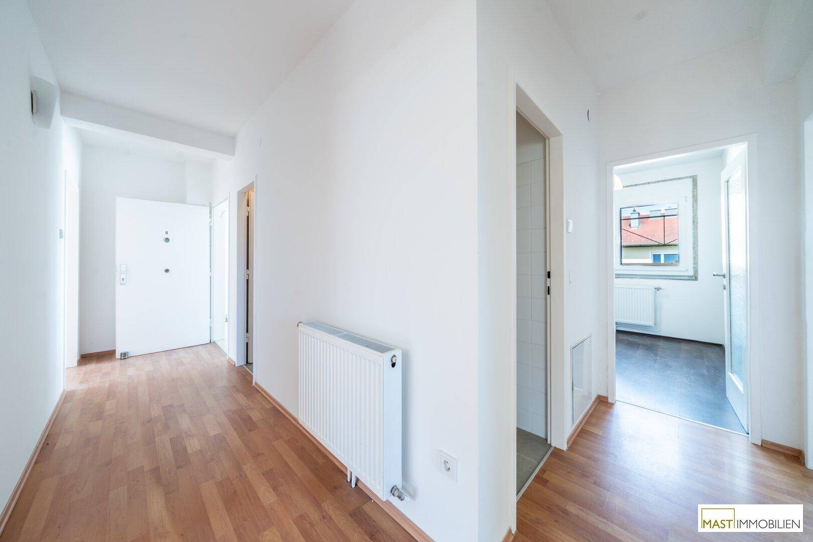 Geräumiger Flur mit Laminatboden, weißen Wänden und Zugang zu verschiedenen Zimmern.