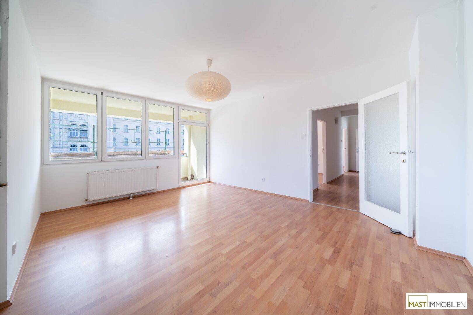 Lichtdurchfluteter Wohnbereich mit Laminatboden und offener Verbindung zum Flur.