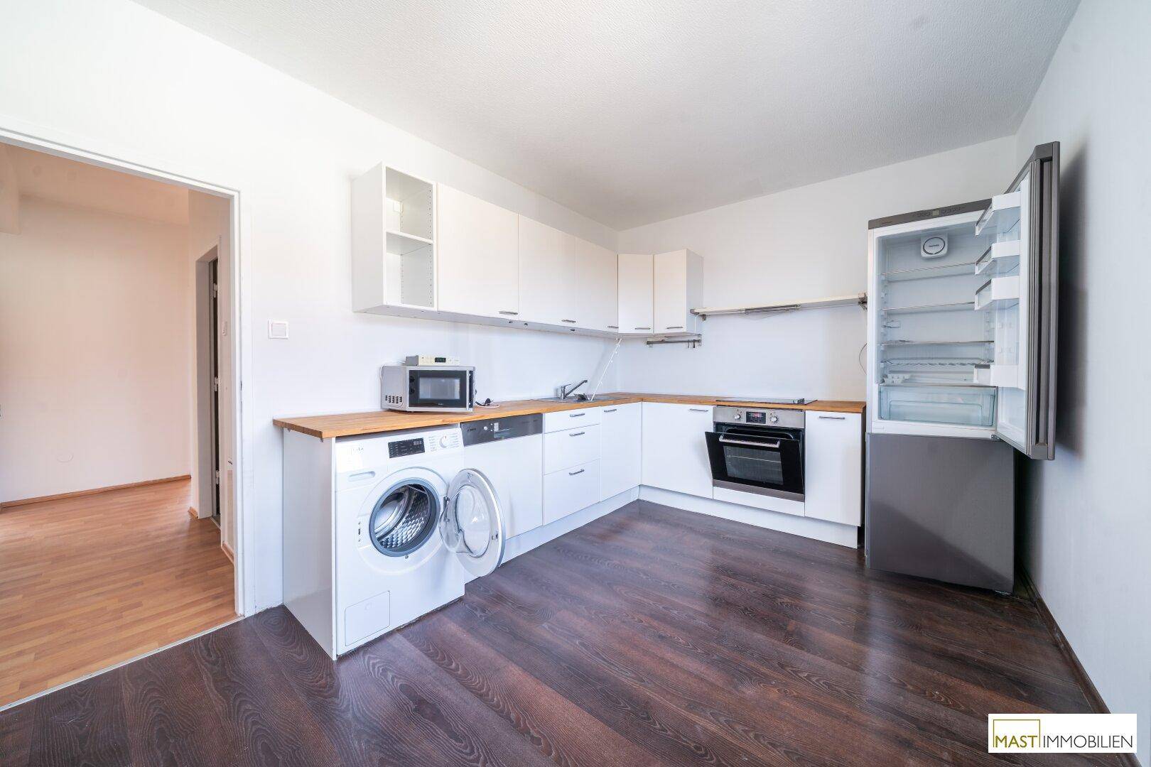 Moderne Küche mit weißen Schränken, Holz-Arbeitsplatten und integrierten Geräten.