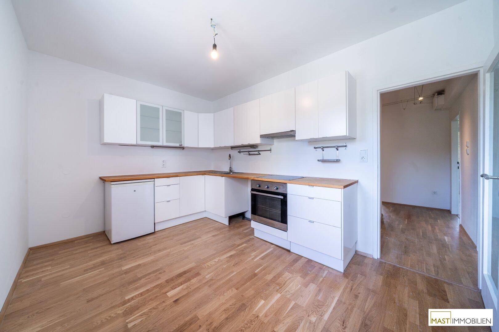 Funktionale Küche mit weißen Schränken, Holz-Arbeitsplatten und integrierten Geräten.