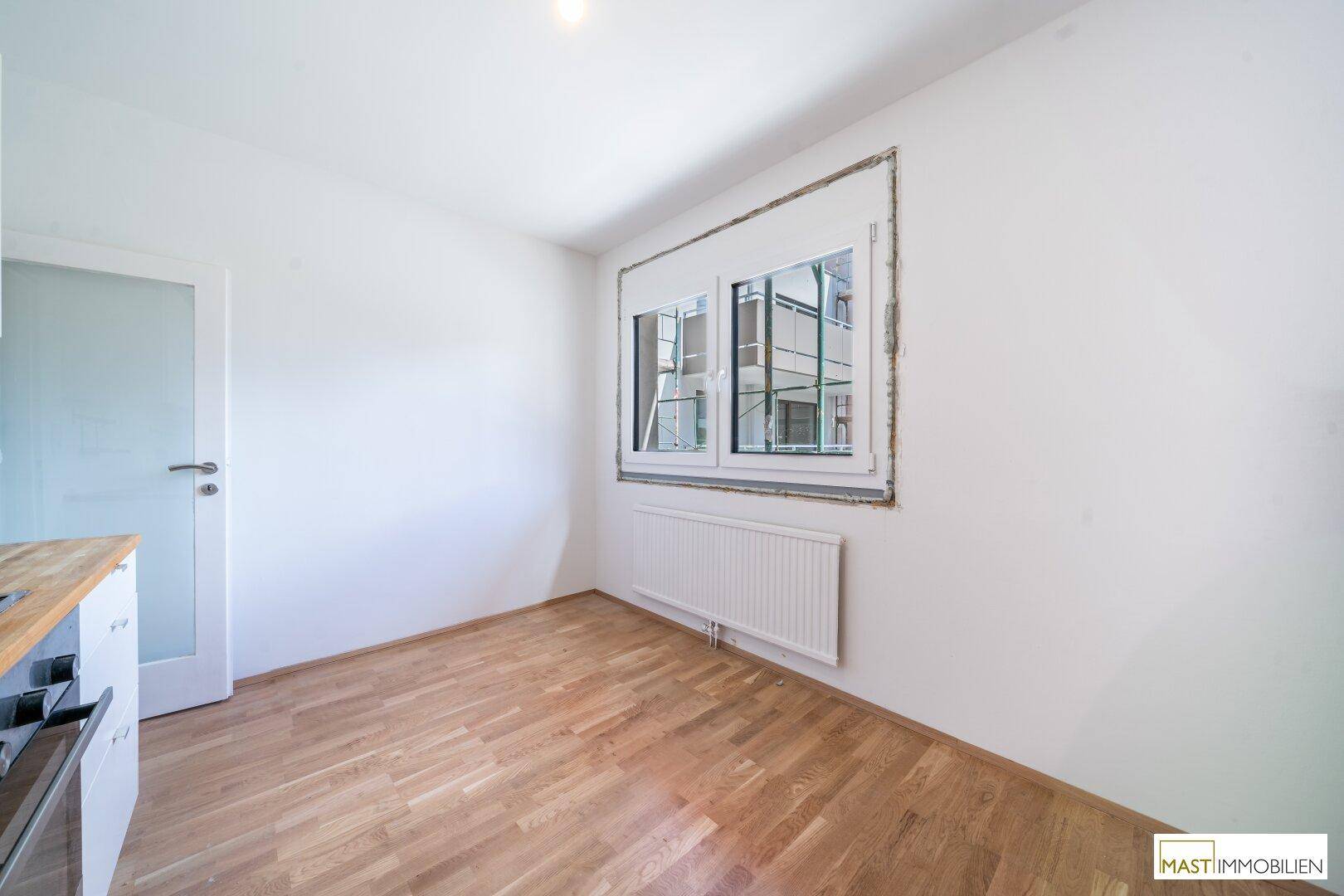 Heller Raum mit Holzboden und Fenster, ideal als Essbereich oder kleines Arbeitszimmer.
