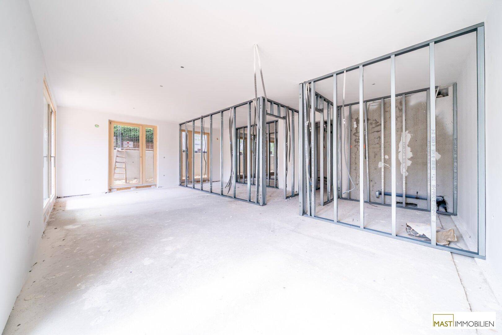Rohbau eines Raumes mit Metallständerwerk zur Raumaufteilung und Blick auf weitere Fenster.