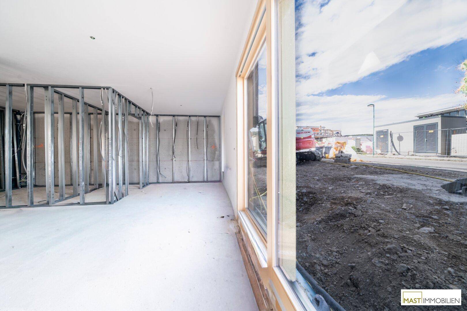 Unfertiger Innenraum mit Metallständerwerk und Blick auf die angrenzende Baustelle.