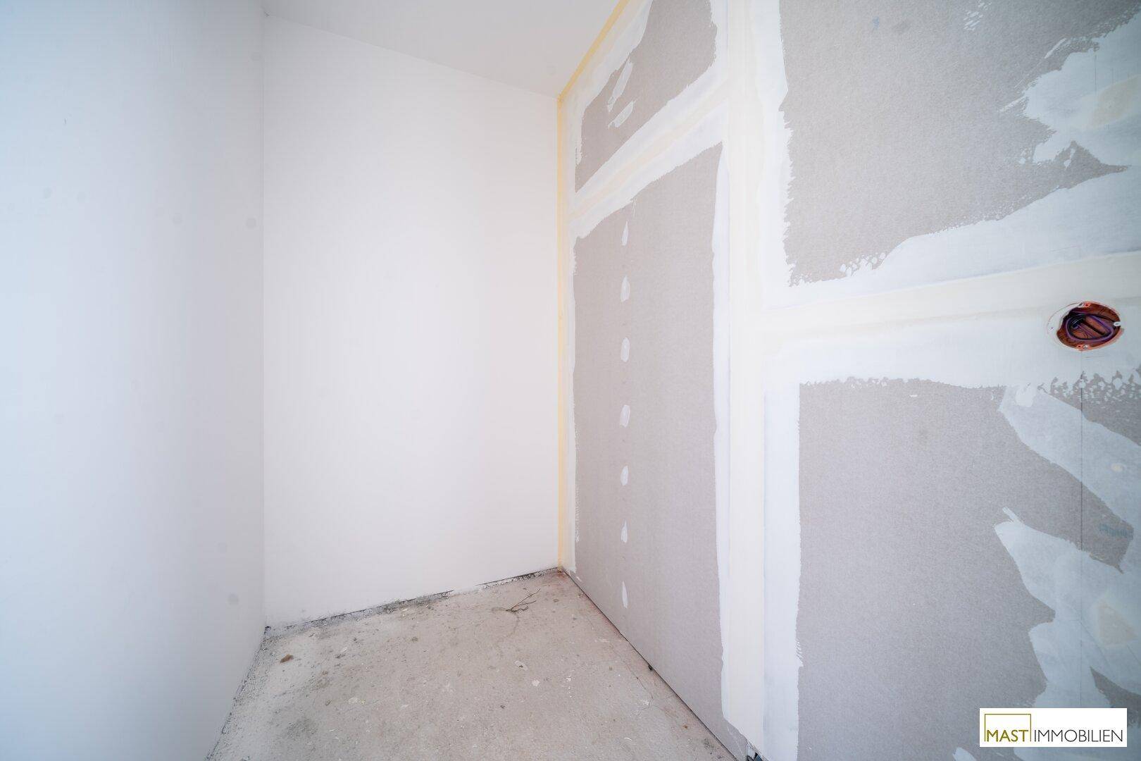 Kleiner Abstellraum im Rohbau mit teilweise verputzten Wänden, bereit für die Fertigstellung.