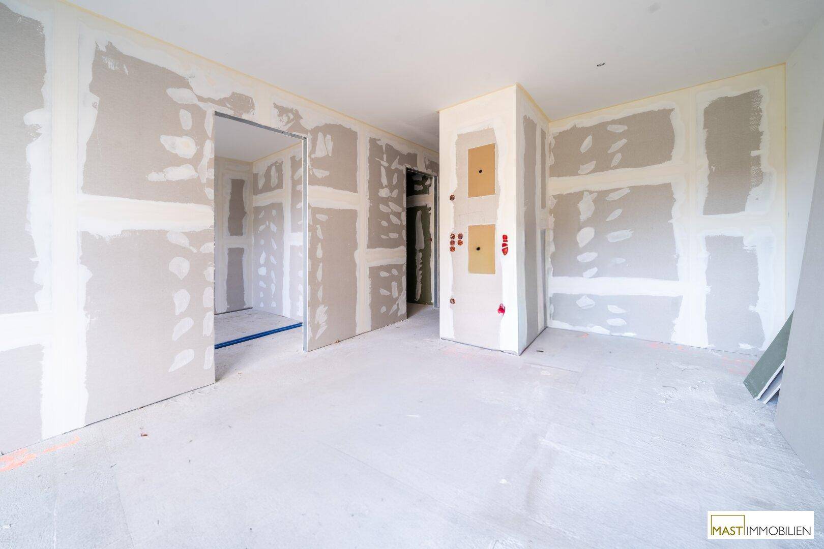 Rohbau eines Innenraums mit Trockenbauwänden und mehreren Türöffnungen, bereit für den weiteren Ausbau.