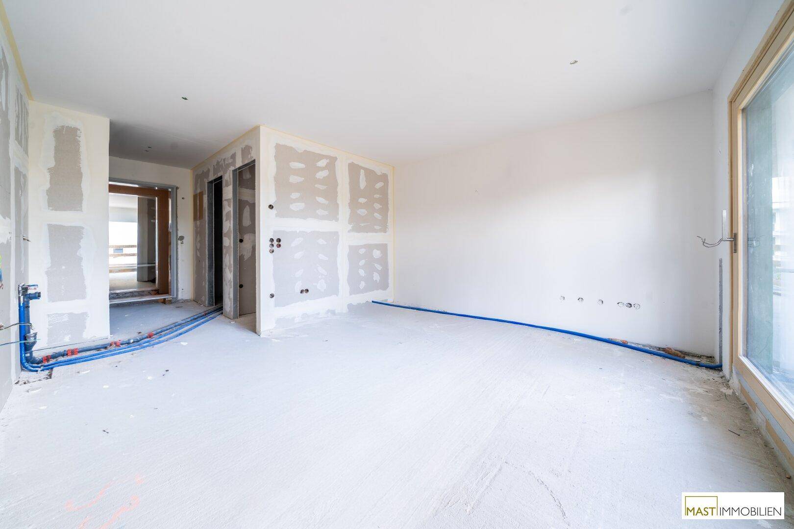Rohbau eines Innenraums mit Trockenbauwänden und sichtbaren Installationen am Boden.