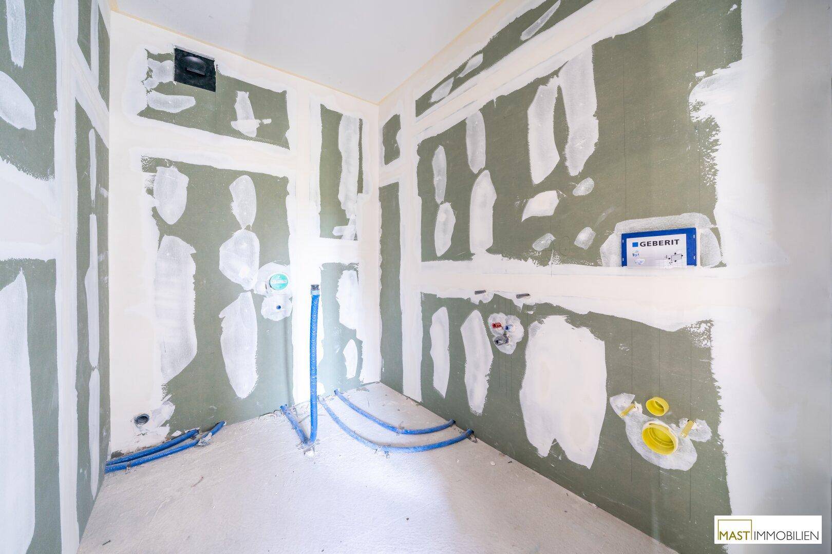 Unfertiges Badezimmer mit sichtbaren Sanitärinstallationen und Trockenbauwänden, bereit für den Ausbau.