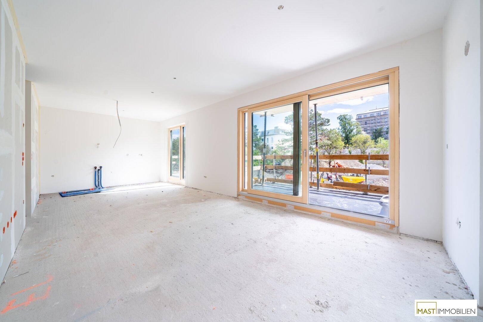 Geräumiger Innenraum im Rohbau mit Schiebetür zu einem zukünftigen Balkon oder Terrasse.