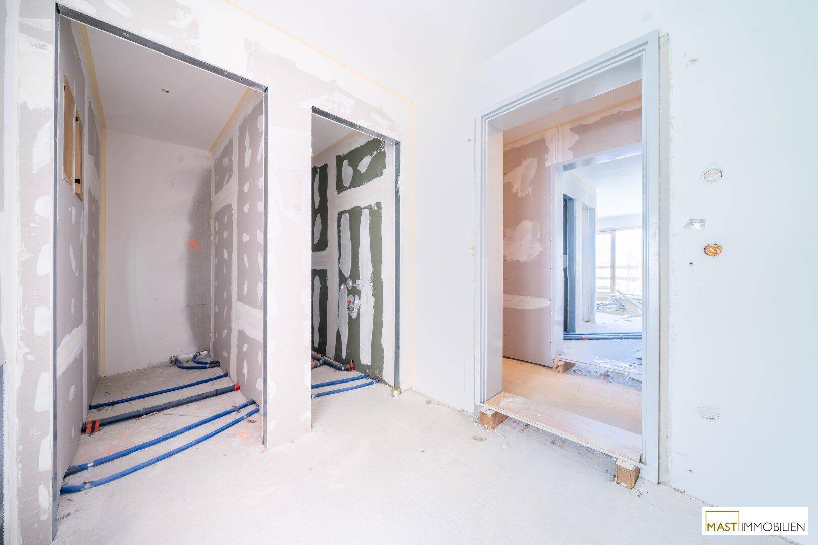 Rohbau eines Flurbereichs mit sichtbaren Installationen und Trockenbauwänden, bereit für den Innenausbau.