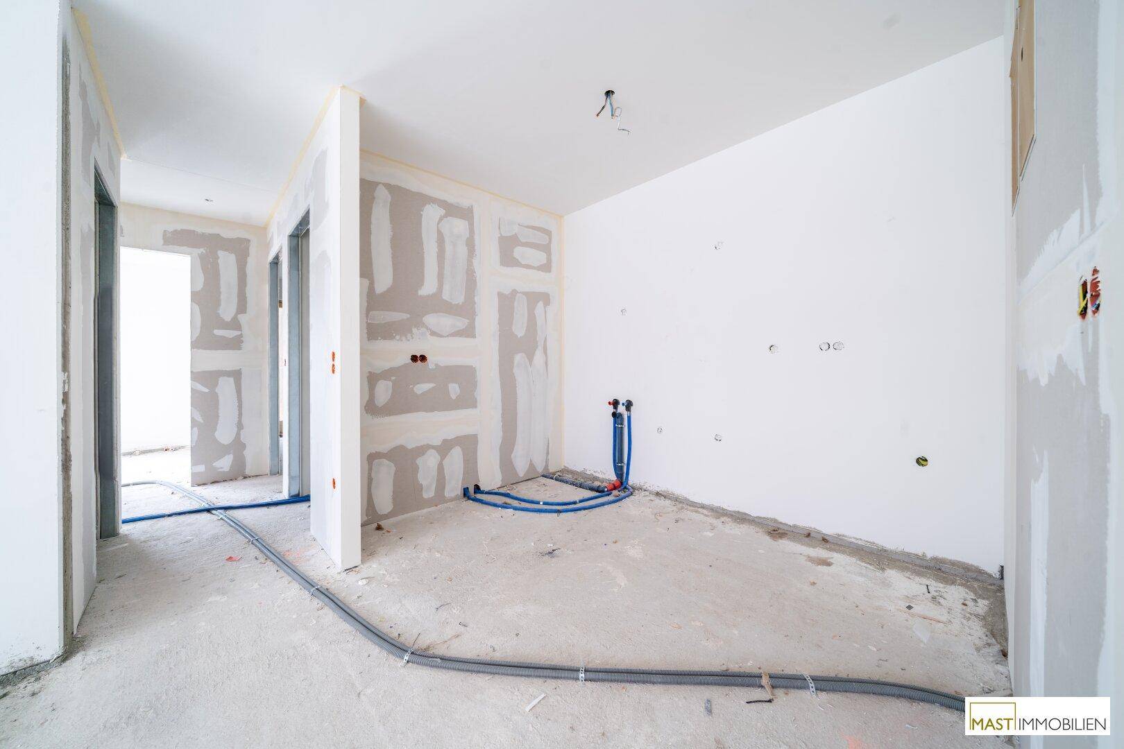 Unfertiger Flurbereich mit sichtbaren Installationen und Rohbauwänden, bereit für den Innenausbau.