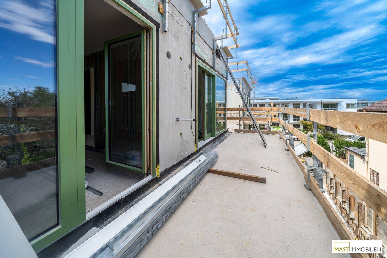 Große Terrasse im Bau mit temporärem Geländer und Blick auf die umliegenden Gebäude.