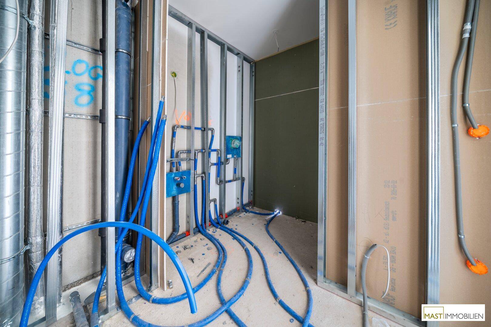 Detailansicht der Rohrleitungen und Lüftungskanäle in einem im Bau befindlichen Raum.