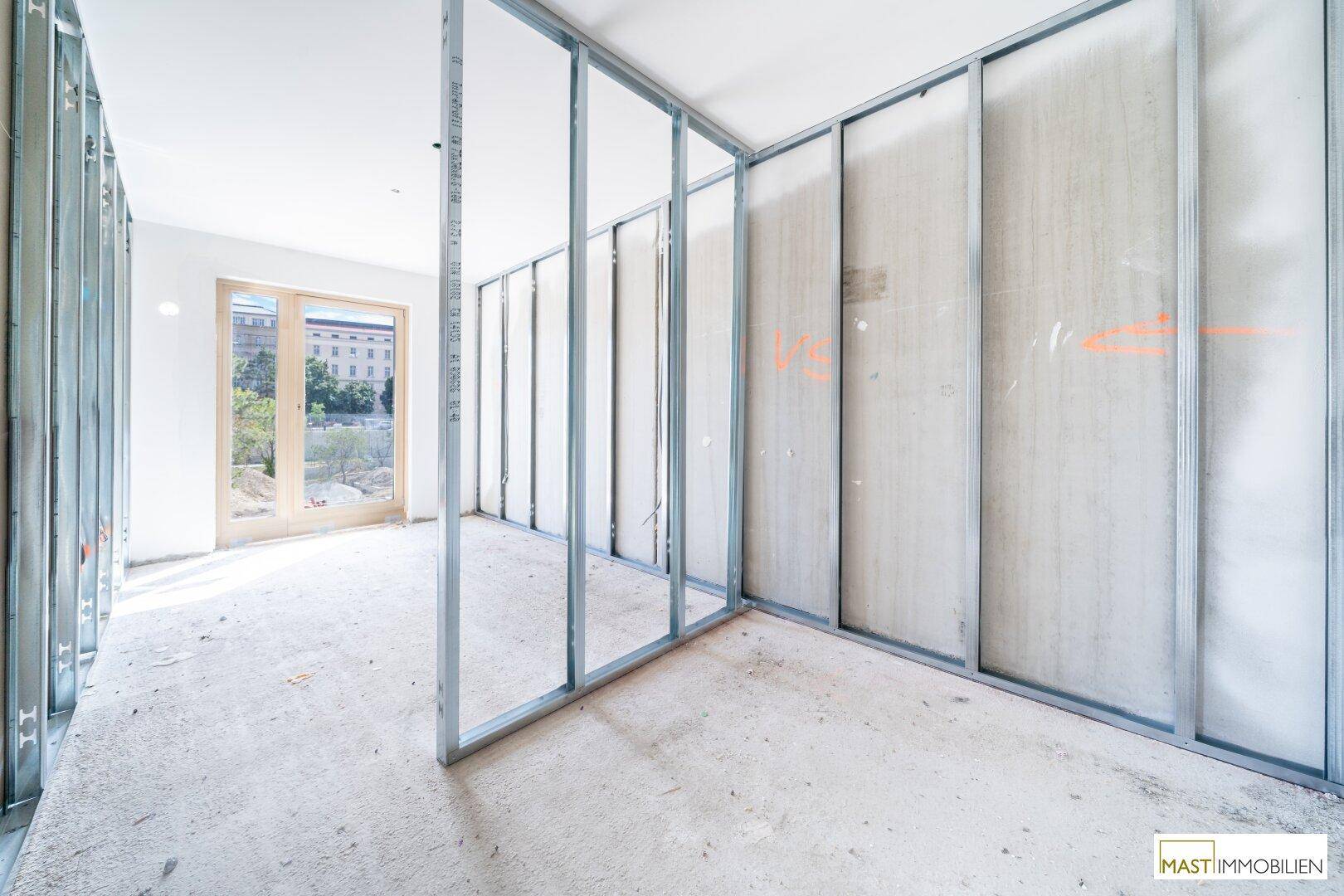 Rohbau-Innenraum mit sichtbarem Metallständerwerk für Trockenbauwände und Blick auf ein Nachbargebäude.