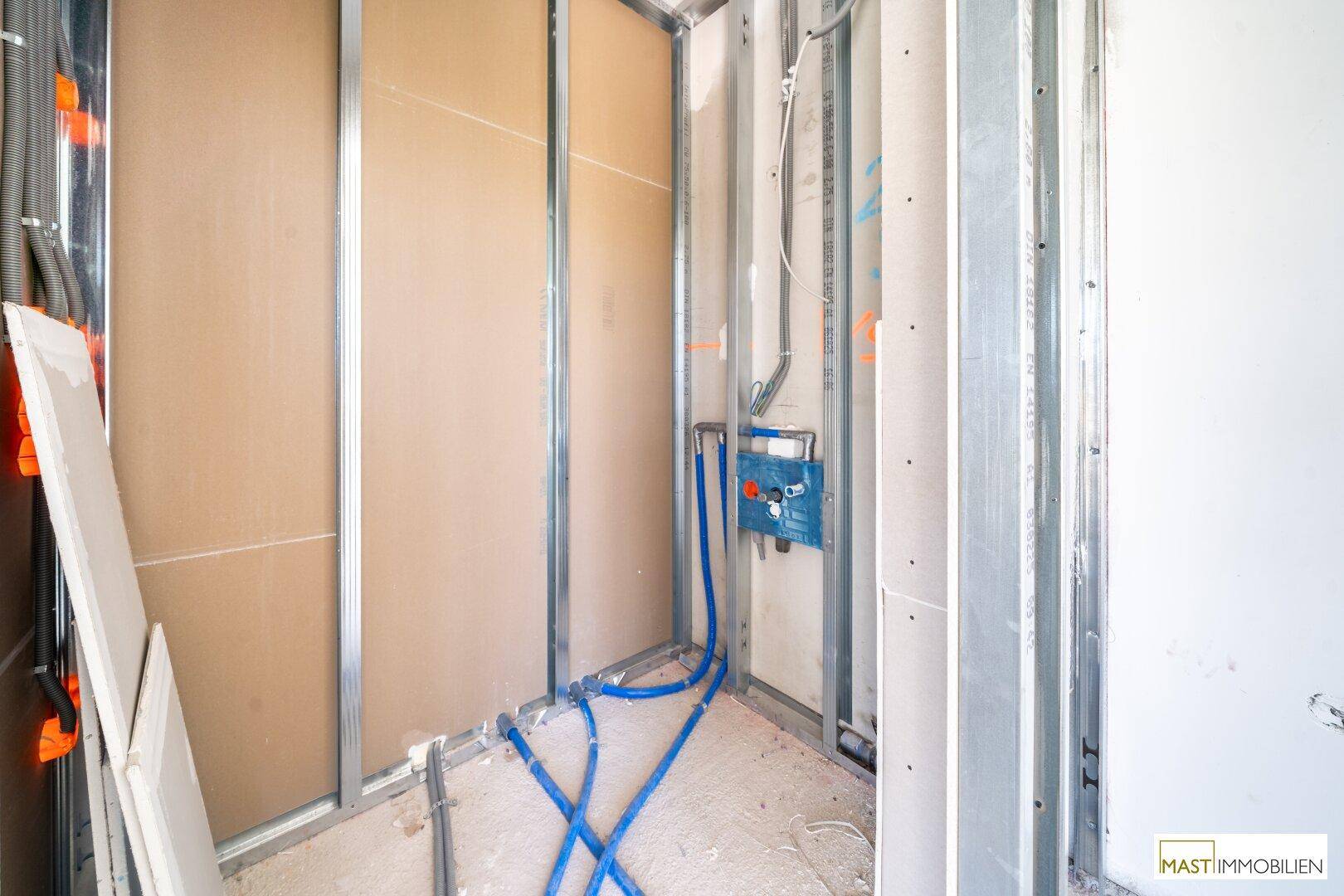 Weiterer Badezimmer-Rohbau mit sichtbaren Wasserinstallationen und Metallständerwerk für die Wandverkleidung.