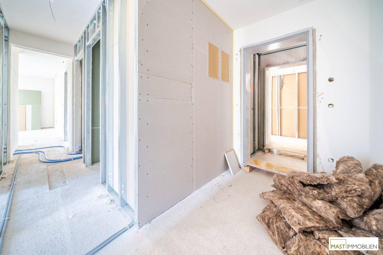 Flur im Rohbau mit Metallständerwerk, Trockenbauplatten und Dämmmaterial, bereit für den Innenausbau.