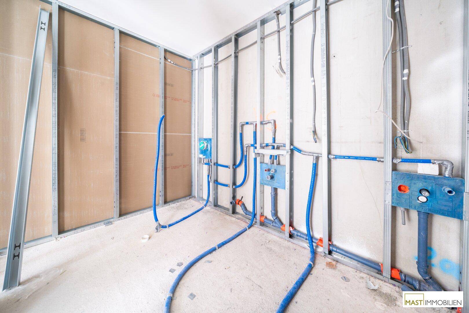Detailansicht der Sanitärinstallationen in einem Badezimmer im Rohbauzustand.