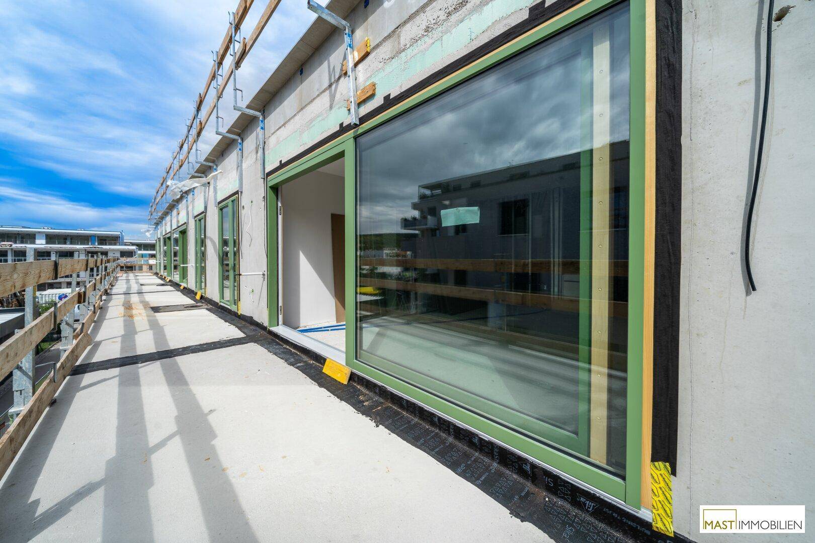 Lange Terrasse im Bau mit großen Schiebetüren und Blick auf die Baustelle.