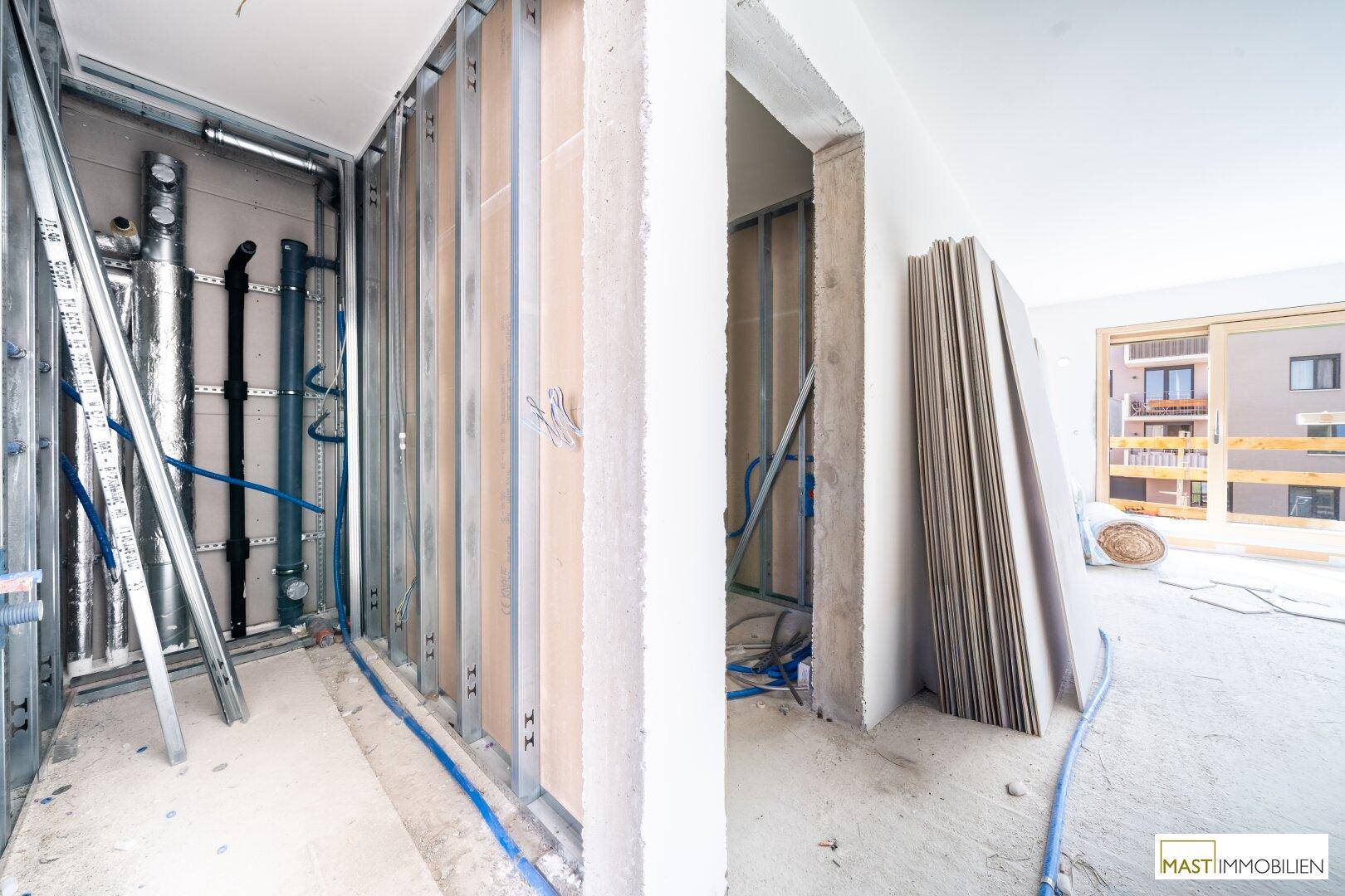 Innenansicht im Rohbau mit Metallständern für Wände und sichtbaren Installationen.